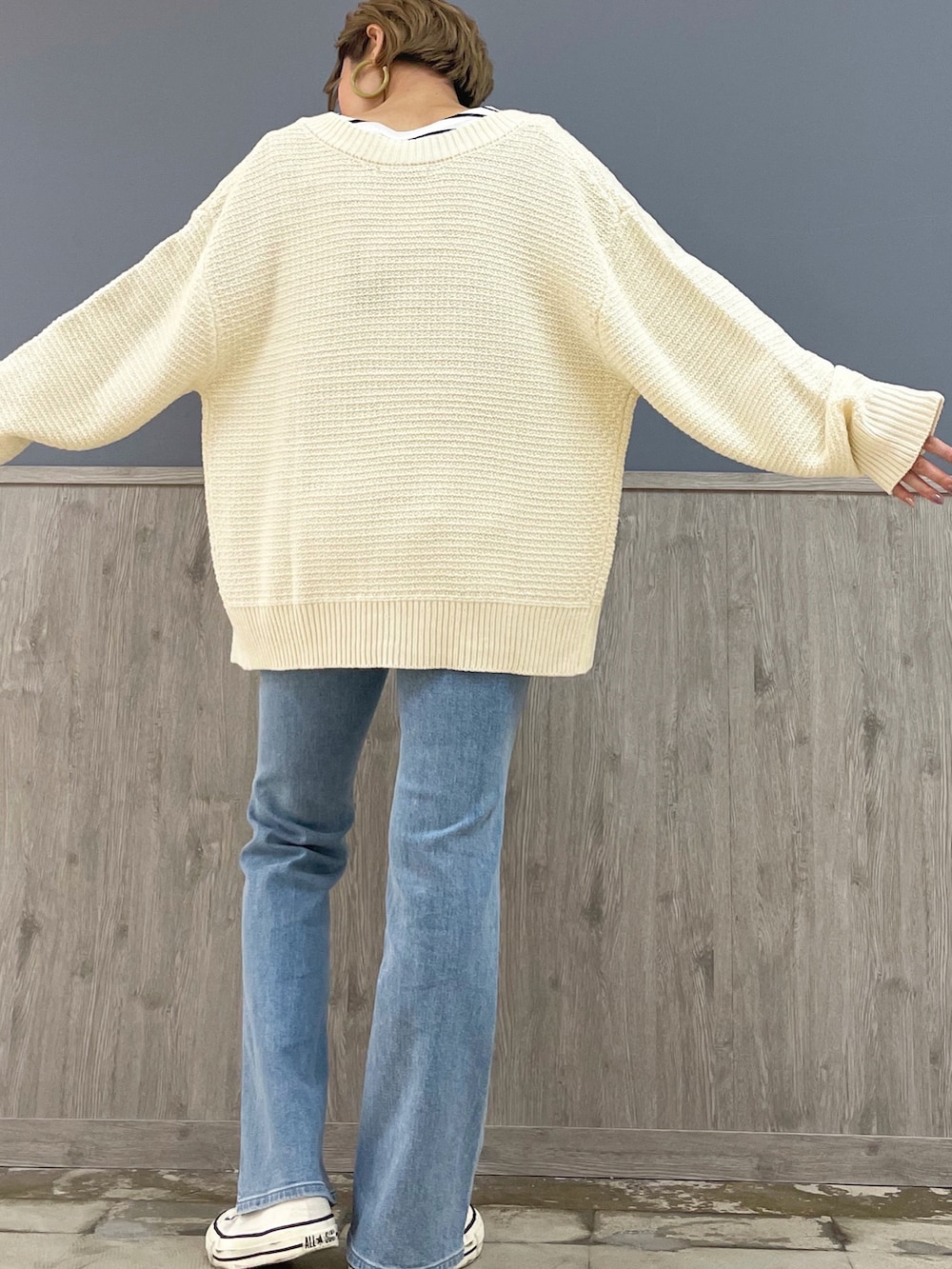 ホワイト系のショルダーバッグ、ホワイト系のカーディガン/ボレロ、ブルー系のデニムパンツを着用したレディースの冬コーディネートの4枚目の写真