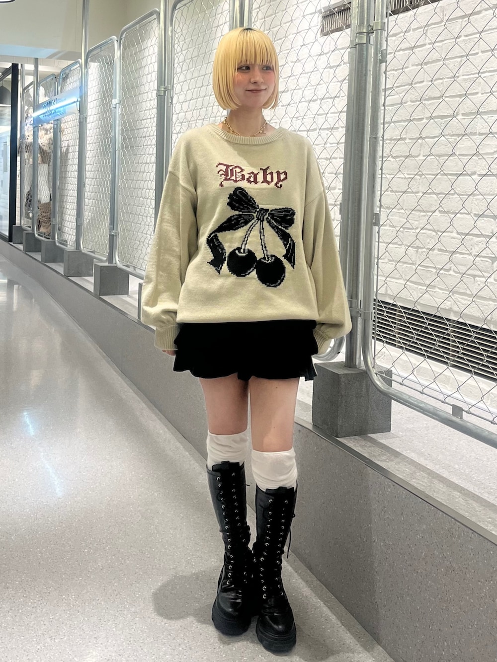 ホワイト系のニット/セーター、ブラック系のスカート、ブラック系のブーツを着用したレディースの秋コーディネートの2枚目の写真