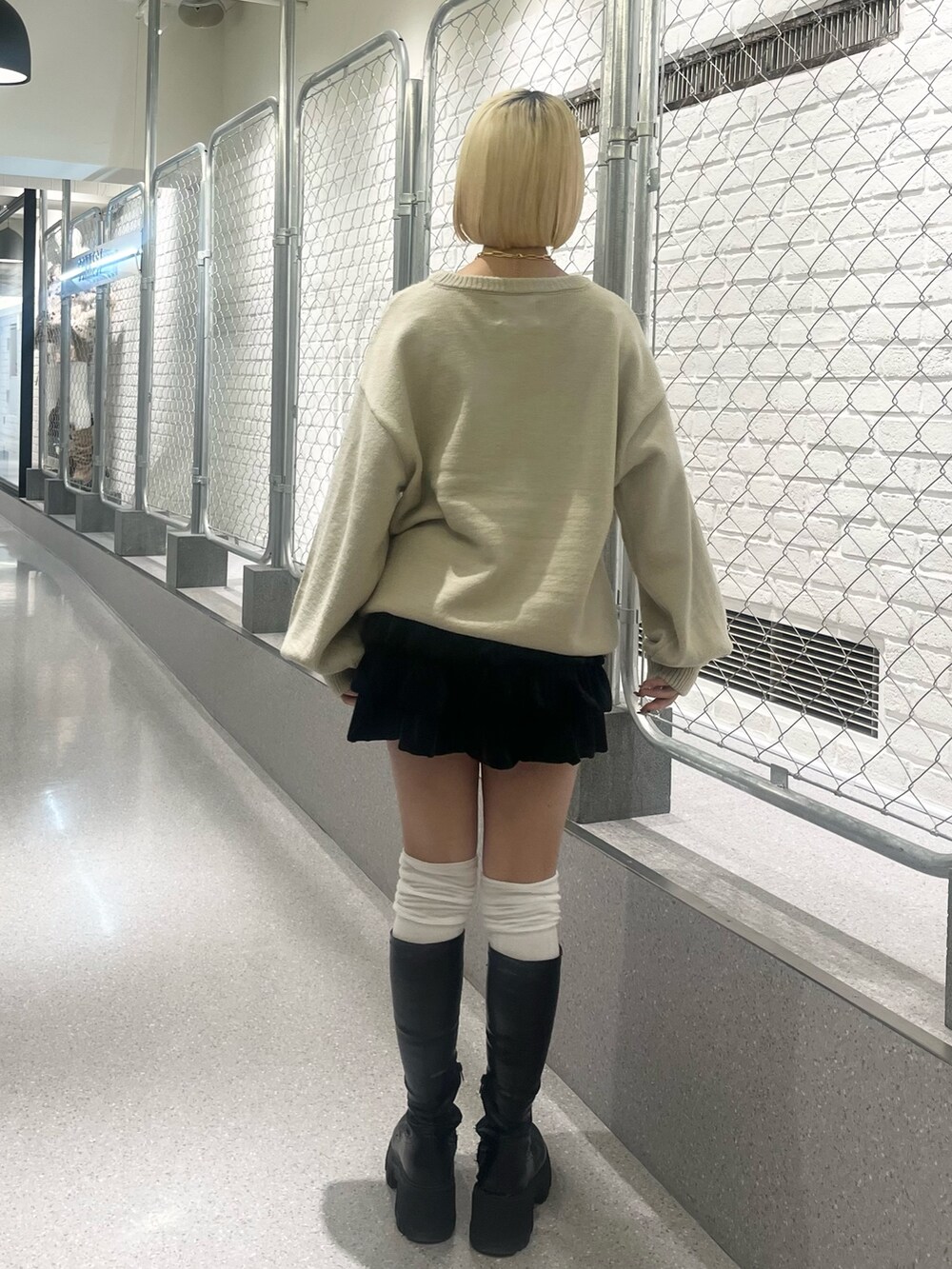 ホワイト系のニット/セーター、ブラック系のスカート、ブラック系のブーツを着用したレディースの秋コーディネートの4枚目の写真