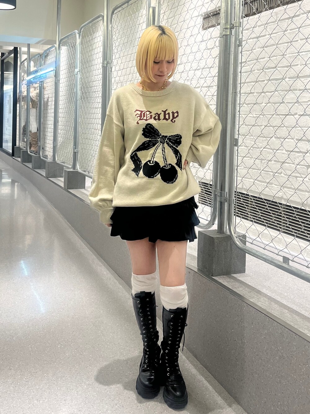 ホワイト系のニット/セーター、ブラック系のスカート、ブラック系のブーツを着用したレディースの秋コーディネートの3枚目の写真