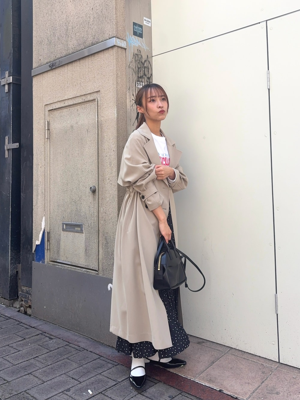 ベージュ系のトレンチコート、ホワイト系のTシャツ/カットソー、ブラック系のパンプスを着用したレディースの春コーディネートの2枚目の写真