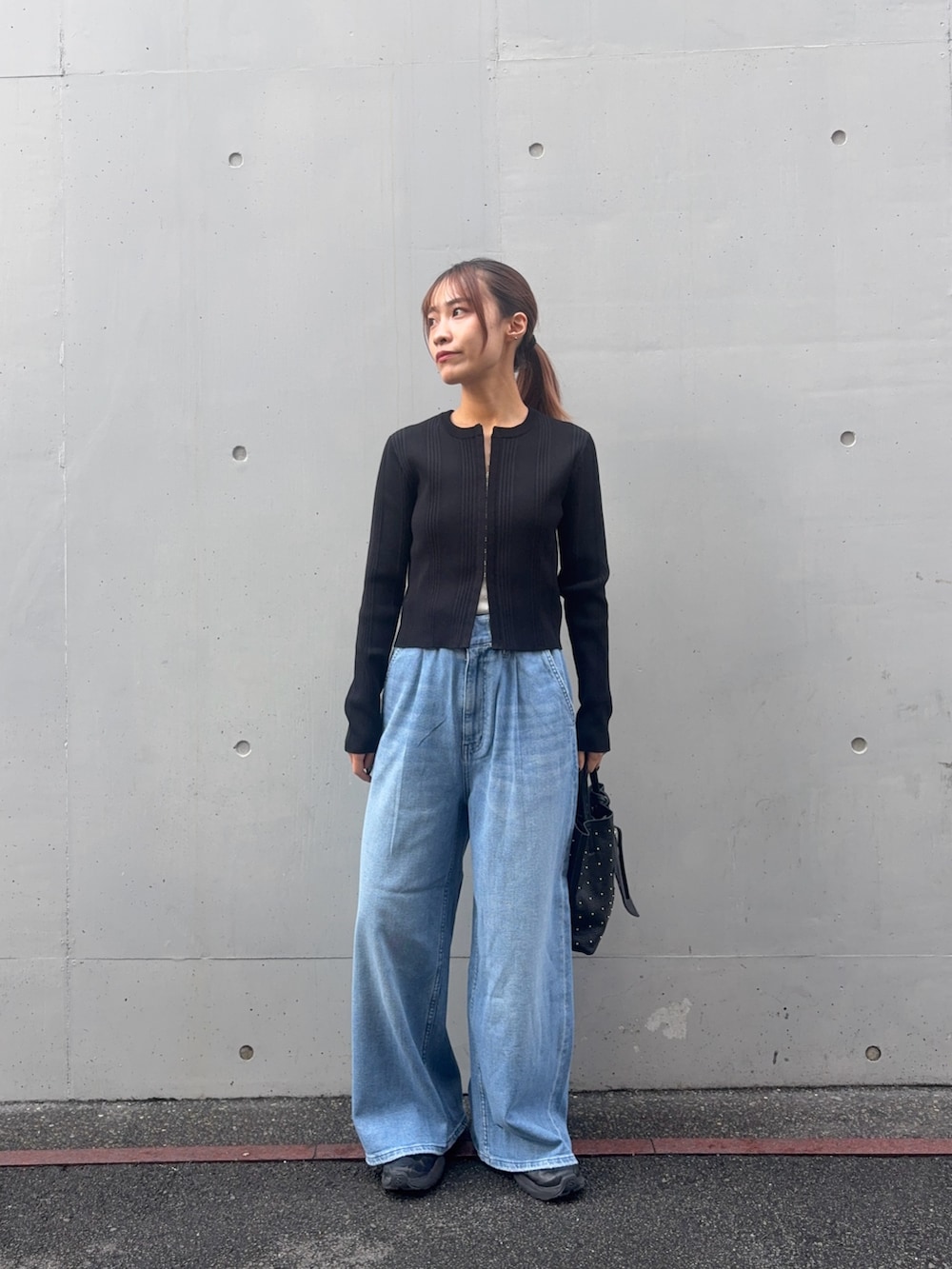 ブラック系のカーディガン/ボレロ、ブルー系のデニムパンツ、ブラック系のトートバッグを着用したレディースの春コーディネートの3枚目の写真