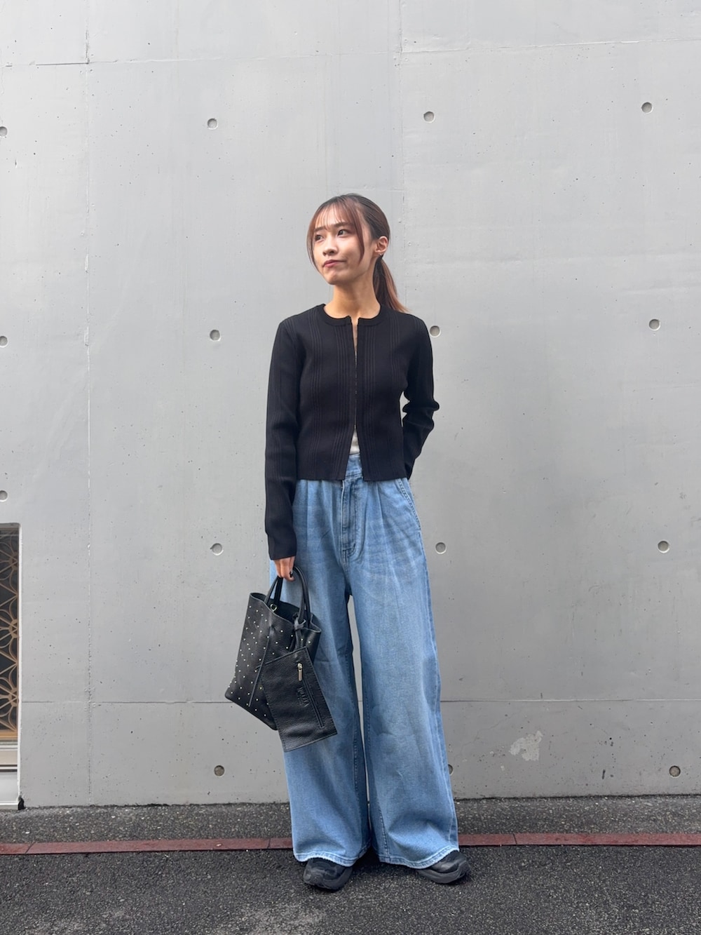 ブラック系のカーディガン/ボレロ、ブルー系のデニムパンツ、ブラック系のトートバッグを着用したレディースの春コーディネートの4枚目の写真