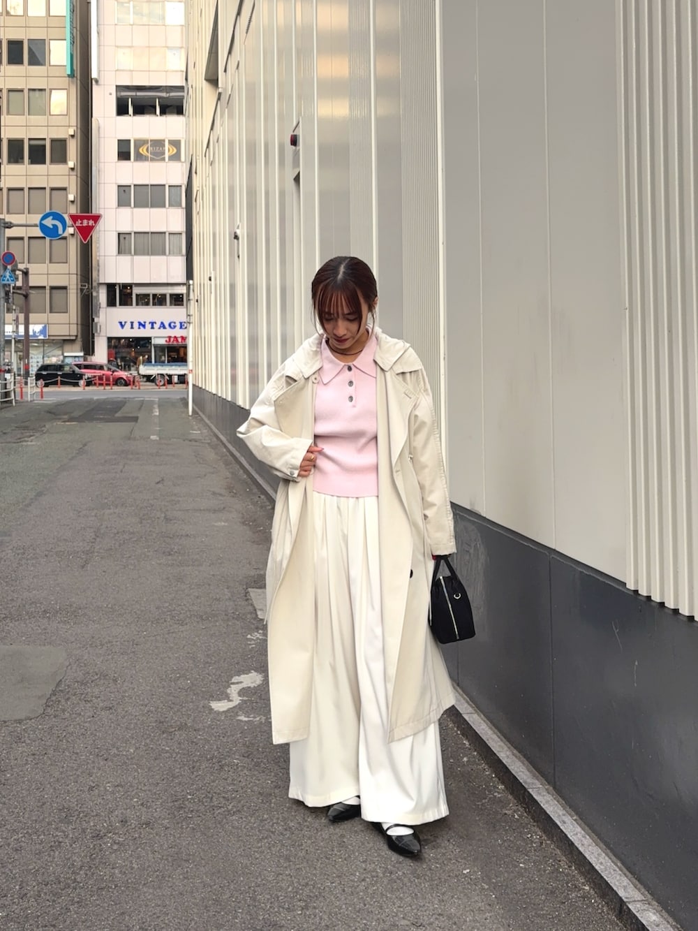ベージュ系のトレンチコート、ホワイト系のその他パンツ、ブラック系のボストンバッグを着用したレディースの冬コーディネートの4枚目の写真