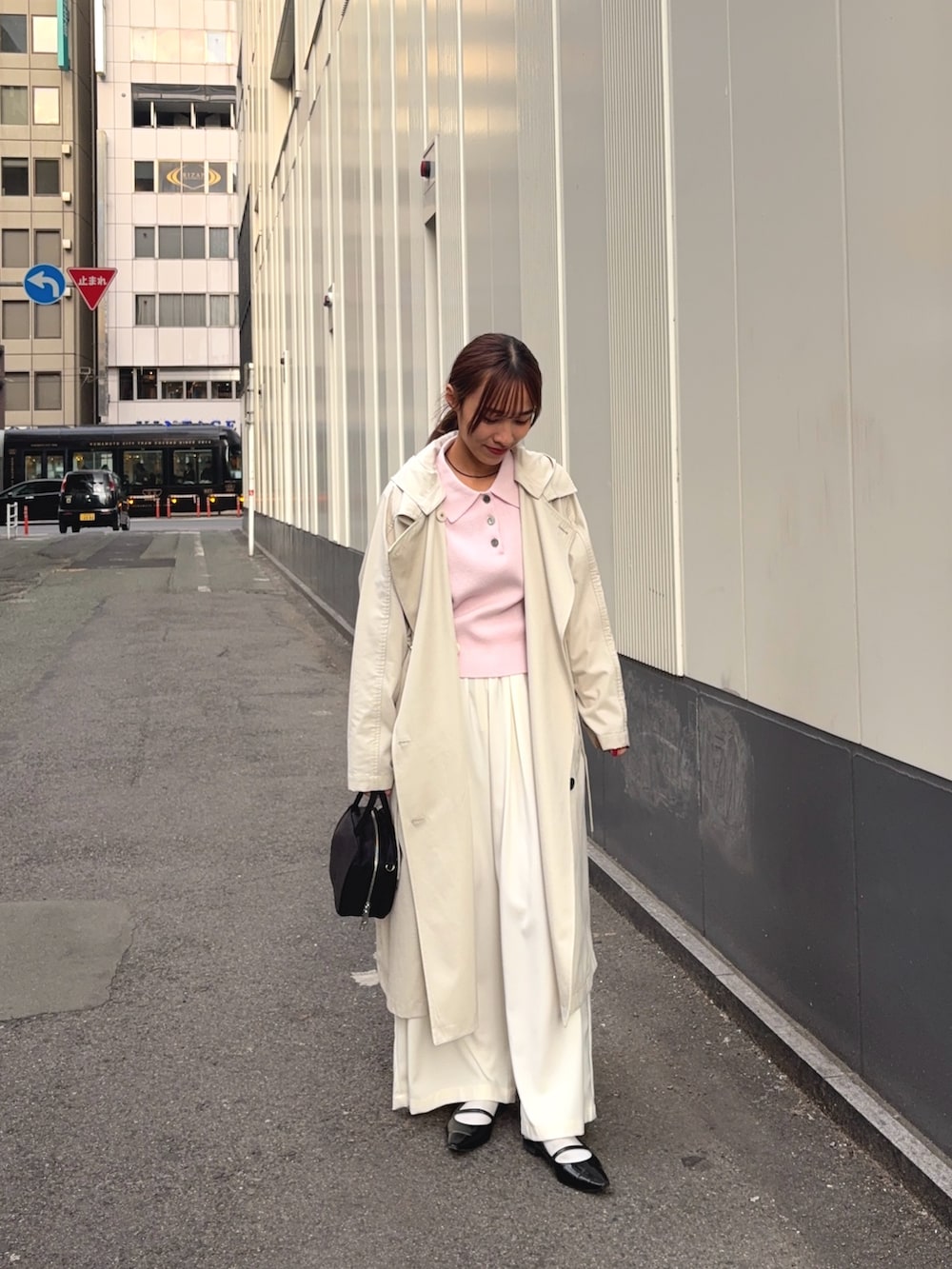 ベージュ系のトレンチコート、ホワイト系のその他パンツ、ブラック系のボストンバッグを着用したレディースの冬コーディネートの3枚目の写真