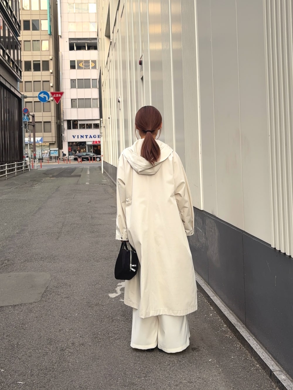 ベージュ系のトレンチコート、ホワイト系のその他パンツ、ブラック系のボストンバッグを着用したレディースの冬コーディネートの5枚目の写真