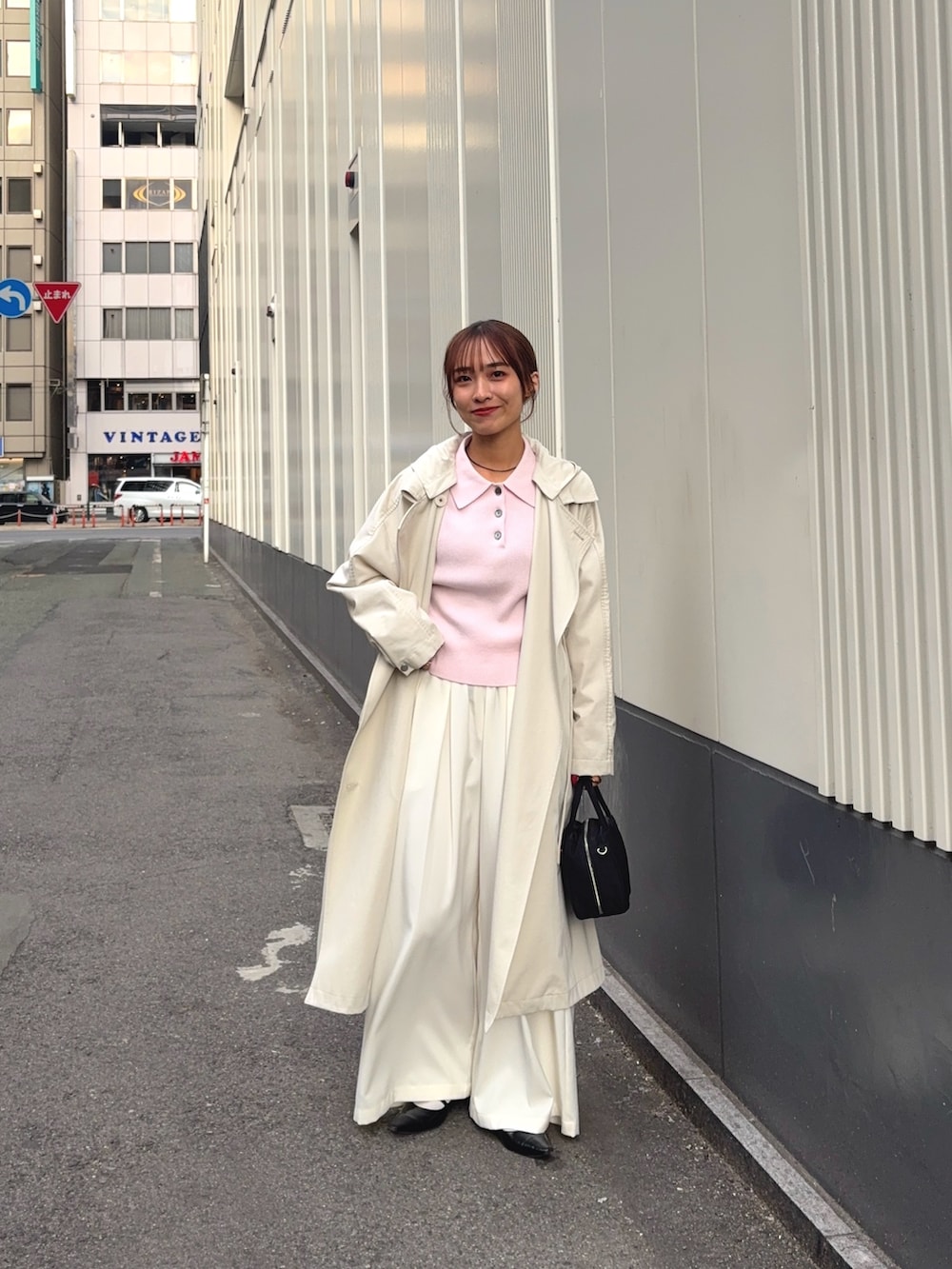 ベージュ系のトレンチコート、ホワイト系のその他パンツ、ブラック系のボストンバッグを着用したレディースの冬コーディネートの2枚目の写真