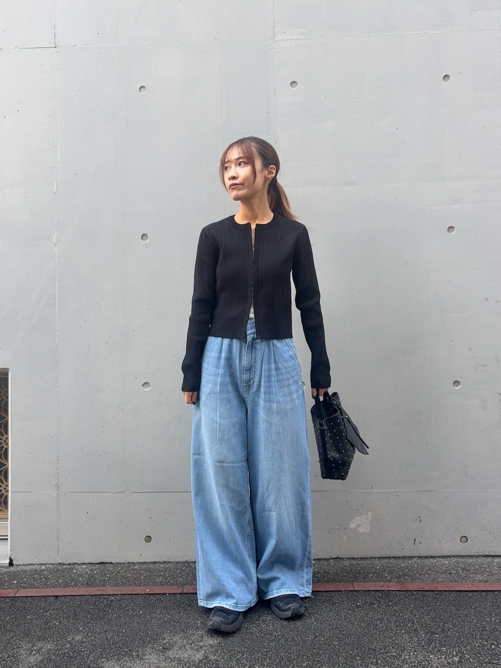 ブラック系のカーディガン/ボレロ、ブルー系のデニムパンツ、ブラック系のトートバッグを着用したレディースの春コーディネートの5枚目の写真