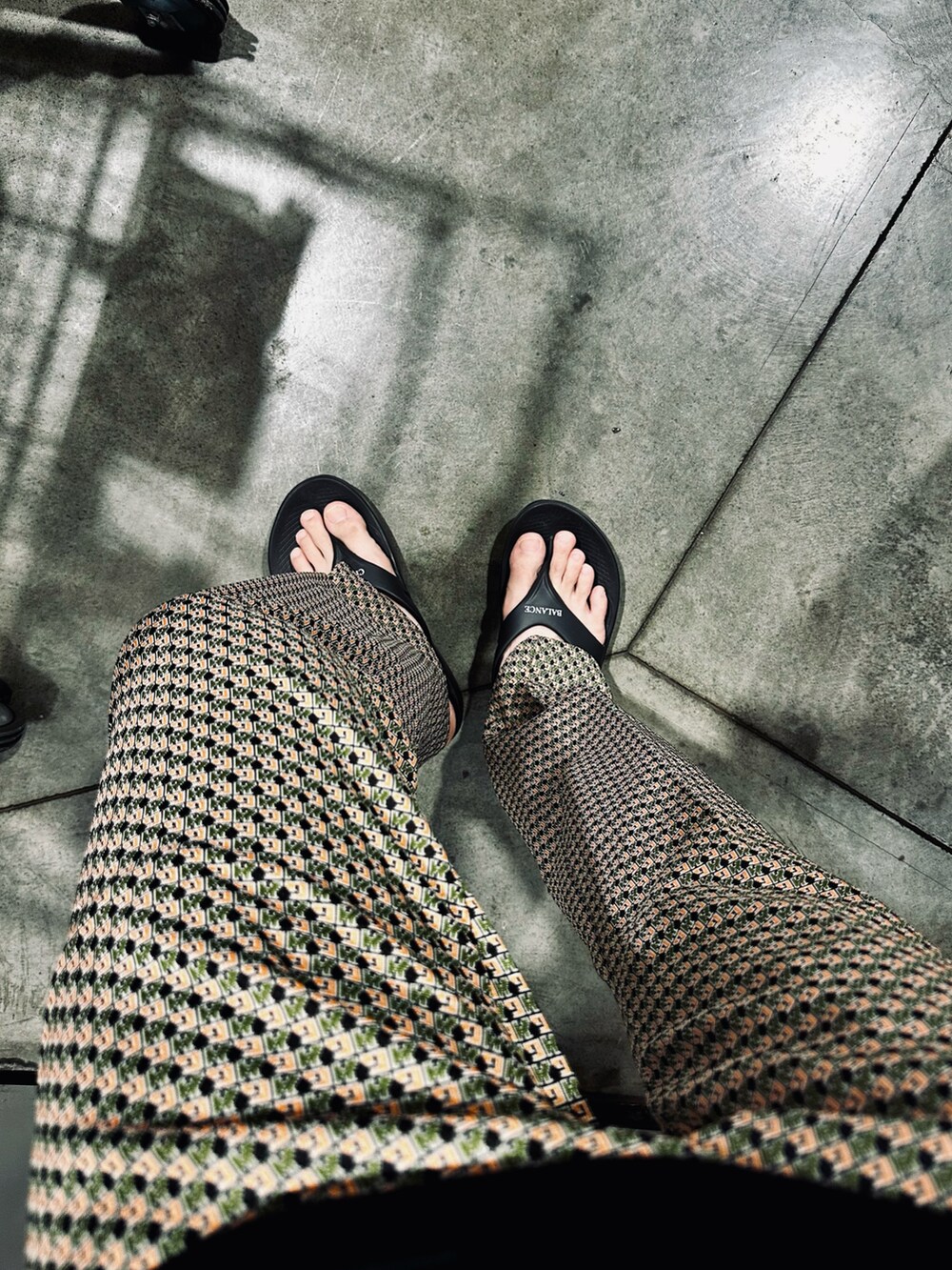 オレンジ系のその他パンツ、ブラック系のTシャツ/カットソー、ブラック系のサンダルを着用したメンズの秋コーディネートの2枚目の写真