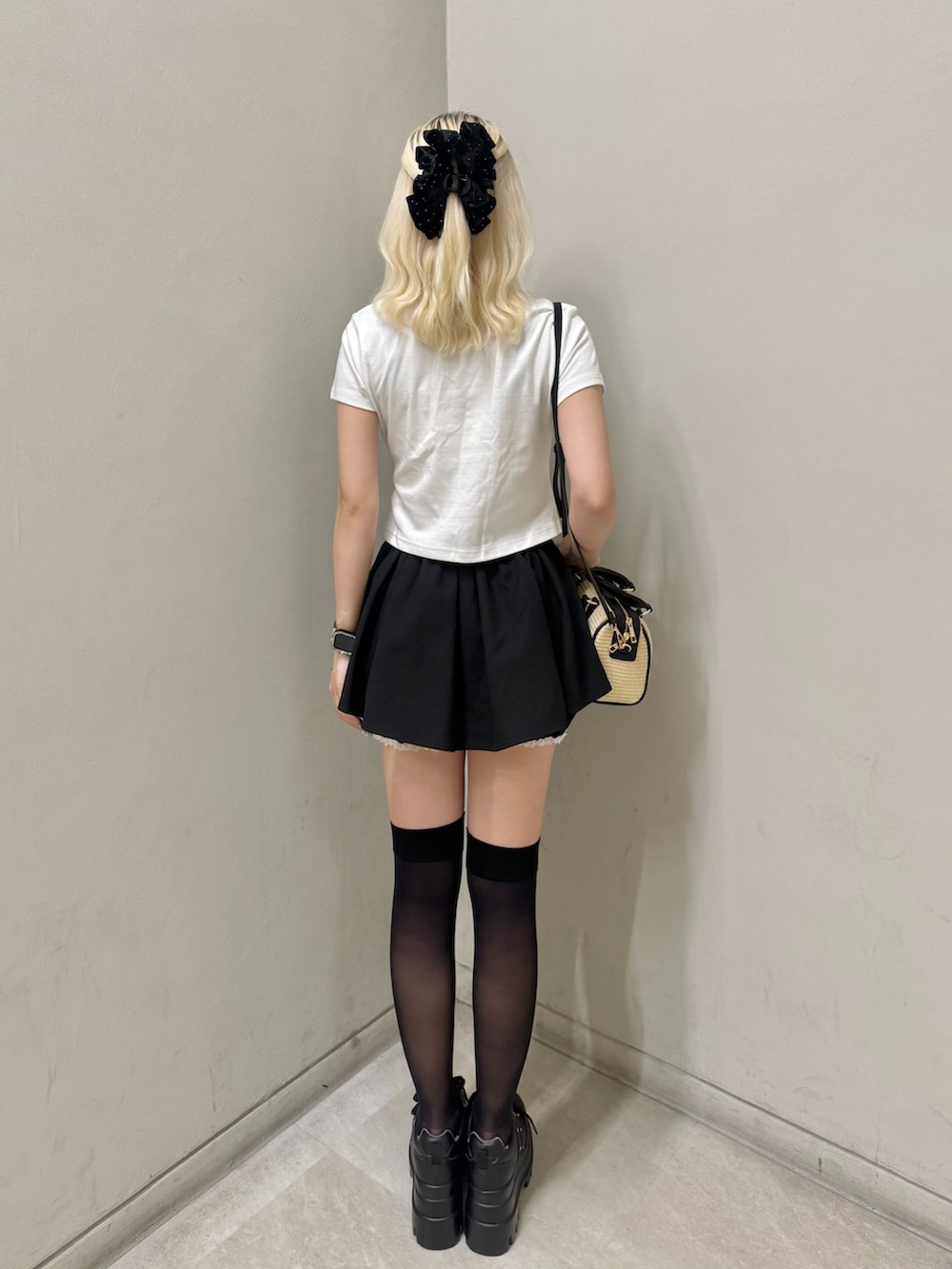 ブラック系のスニーカー、ホワイト系のTシャツ/カットソー、ブラック系のショルダーバッグを着用したレディースの夏コーディネートの3枚目の写真