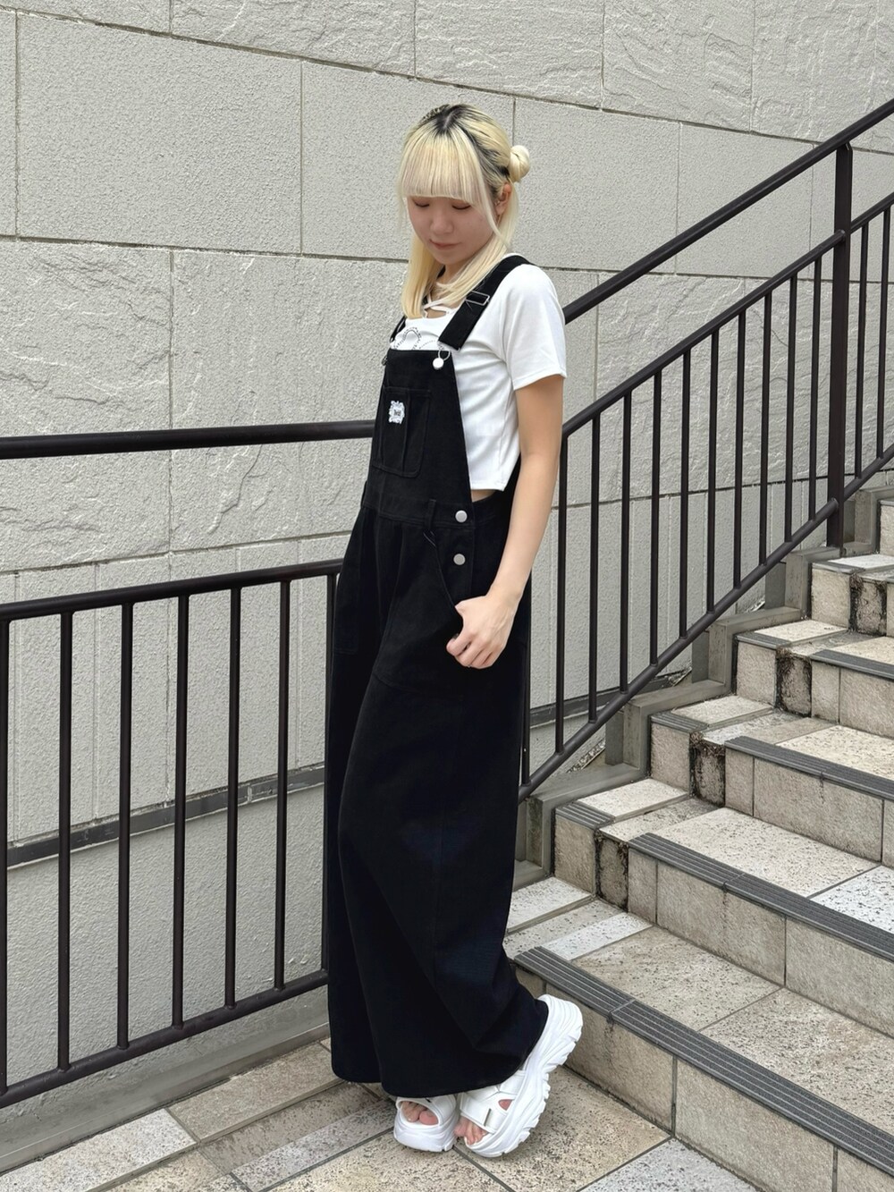 ブラック系のサロペット/オーバーオール、ホワイト系のTシャツ/カットソー、ホワイト系のサンダルを着用したレディースの夏コーディネートの2枚目の写真