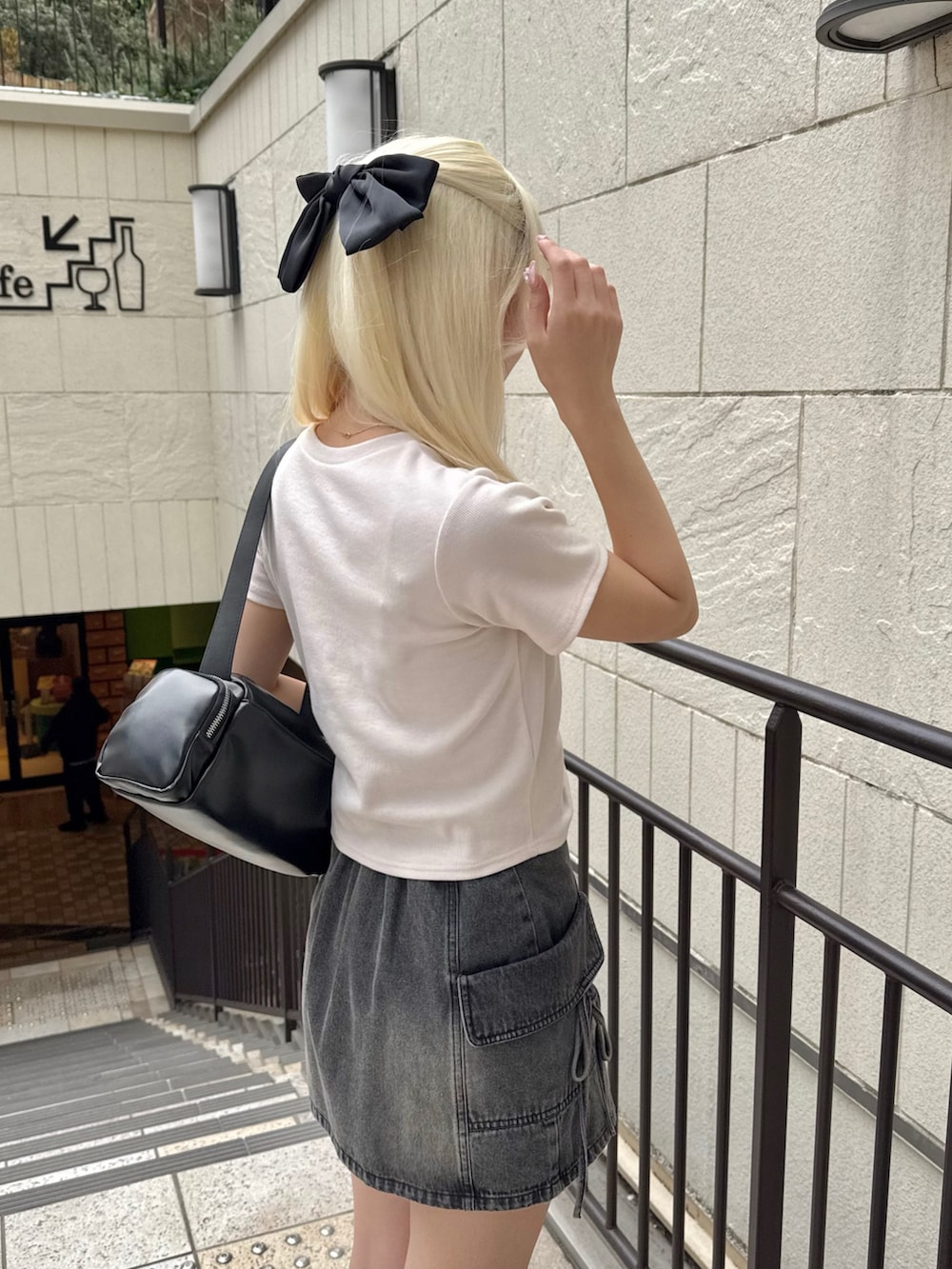 ブラック系のショルダーバッグ、ピンク系のTシャツ/カットソー、ブラック系のスカートを着用したレディースの春コーディネートの6枚目の写真