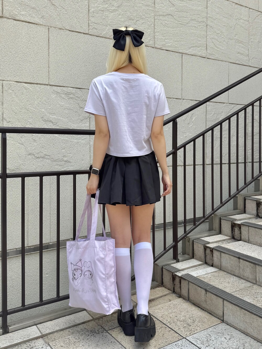 パープル系のトートバッグ、パープル系のTシャツ/カットソー、ブラック系のスカートを着用したレディースの夏コーディネートの4枚目の写真