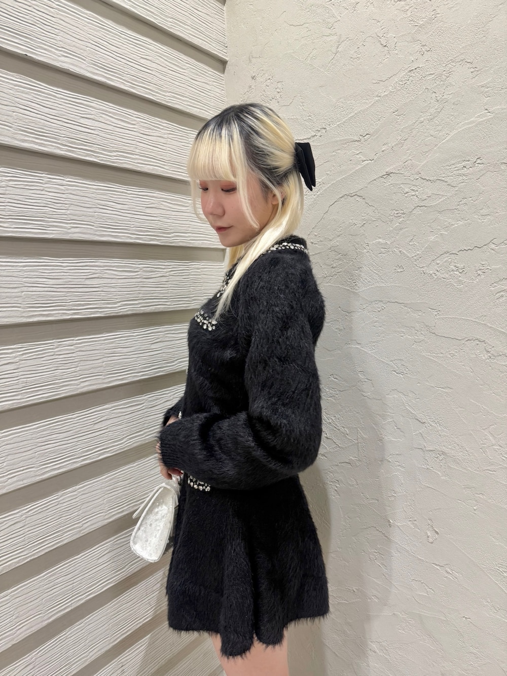 ブラック系のセットアップ、ホワイト系のショルダーバッグ、ブラック系のブーツを着用したレディースの冬コーディネートの5枚目の写真