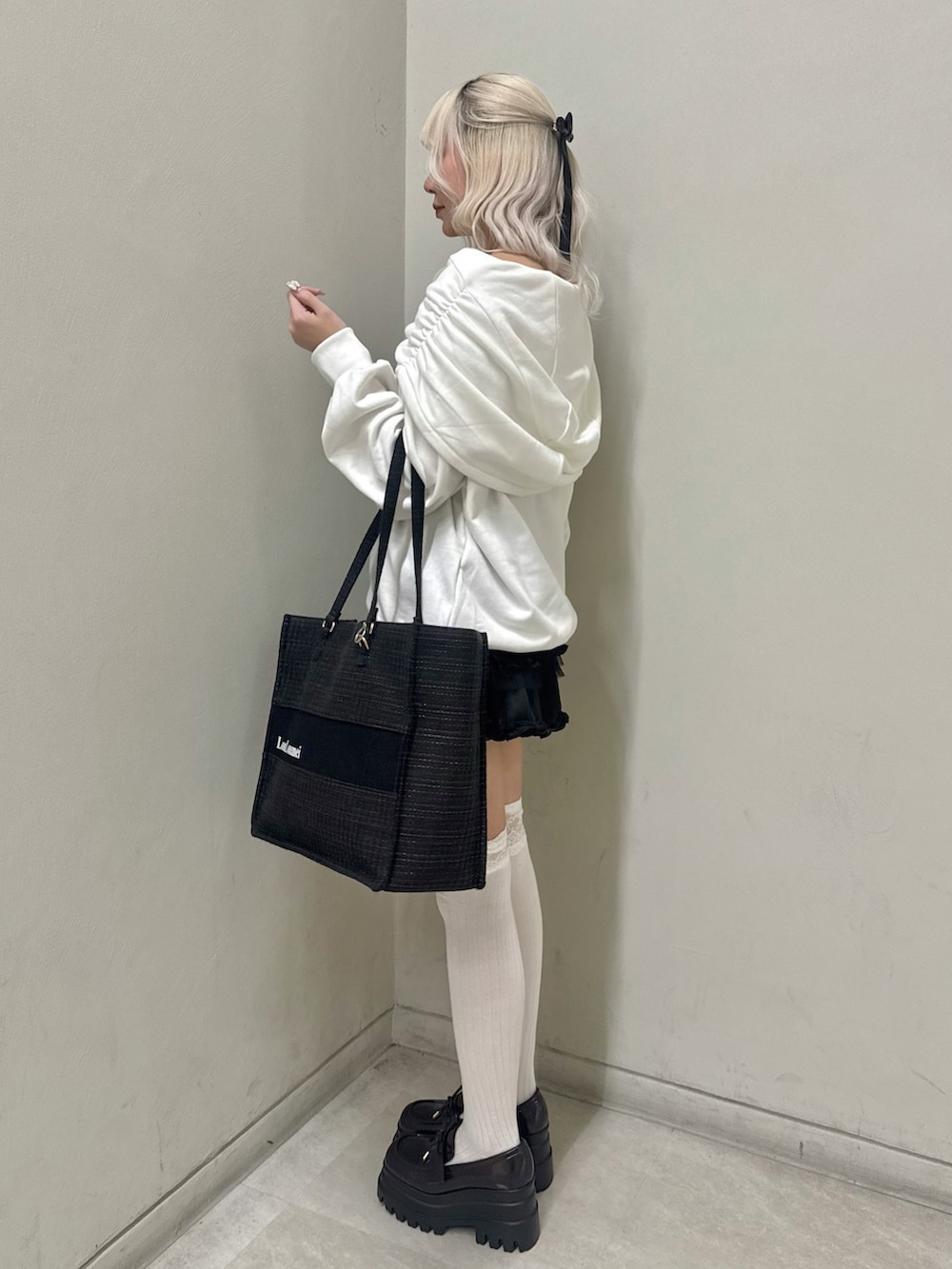 ホワイト系のパーカー、ブラック系のトートバッグ、ブラック系のスカートを着用したレディースの春コーディネートの2枚目の写真