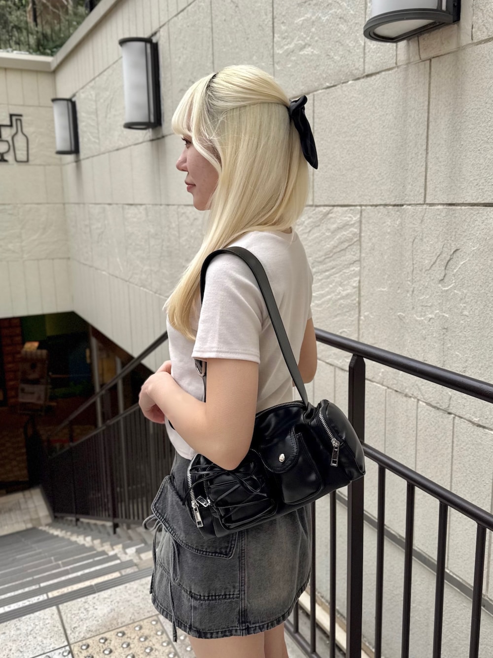 ブラック系のショルダーバッグ、ピンク系のTシャツ/カットソー、ブラック系のスカートを着用したレディースの春コーディネートの5枚目の写真