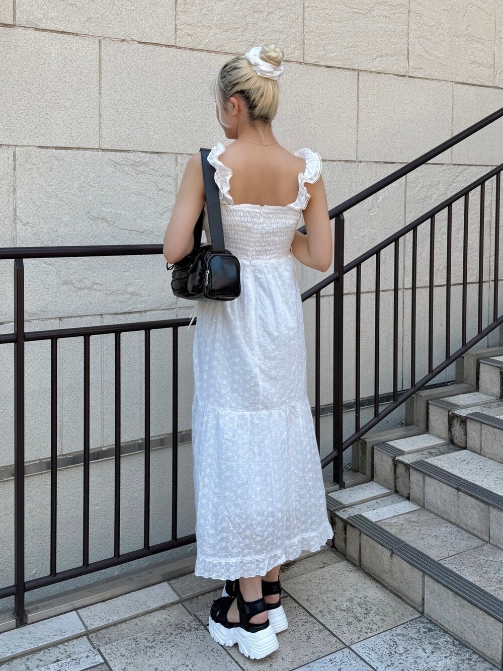 ブルー系のデニムジャケット、ブラック系のショルダーバッグ、ホワイト系のワンピースを着用したレディースの春コーディネートの5枚目の写真