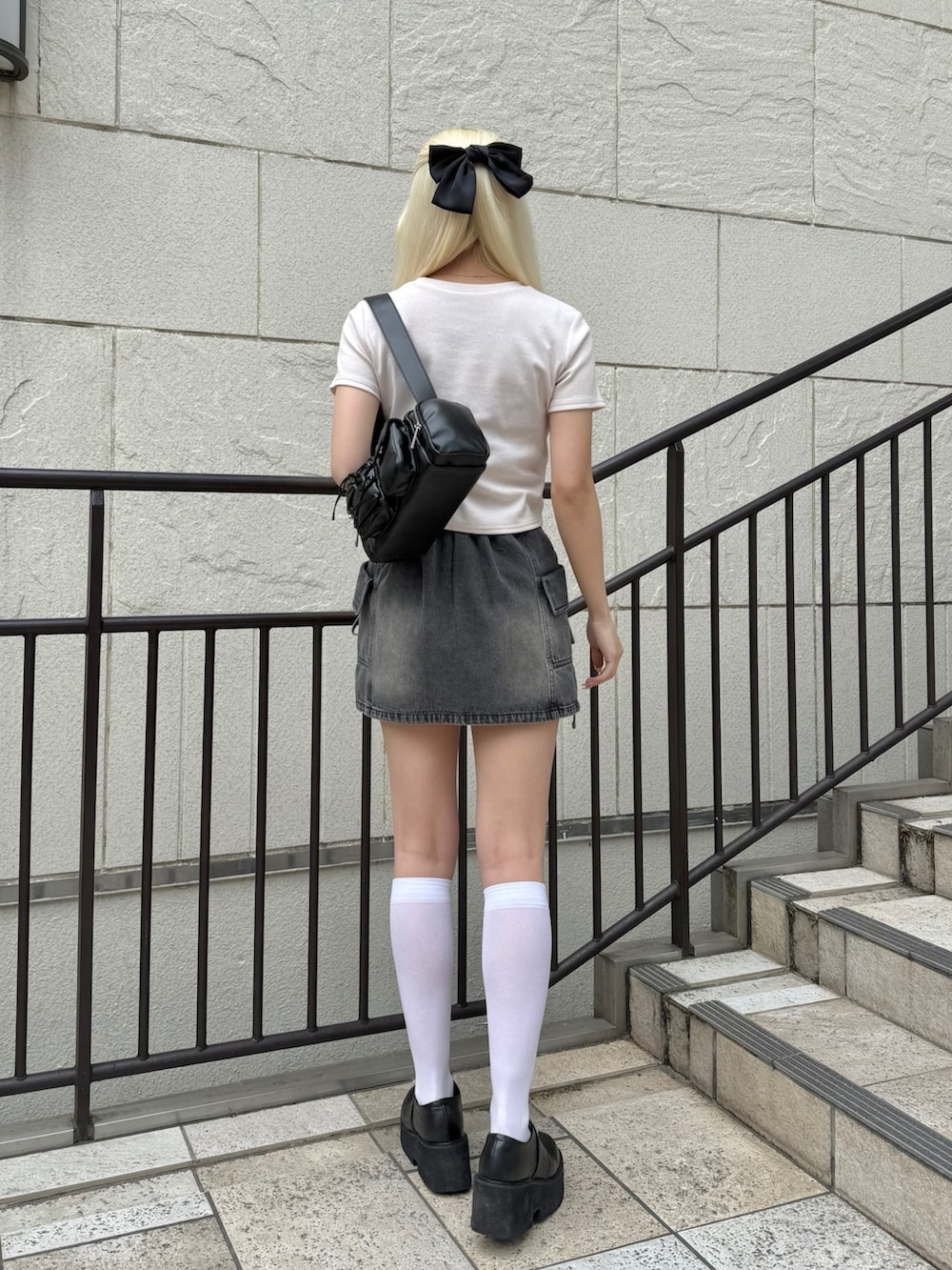 ブラック系のショルダーバッグ、ピンク系のTシャツ/カットソー、ブラック系のスカートを着用したレディースの春コーディネートの3枚目の写真