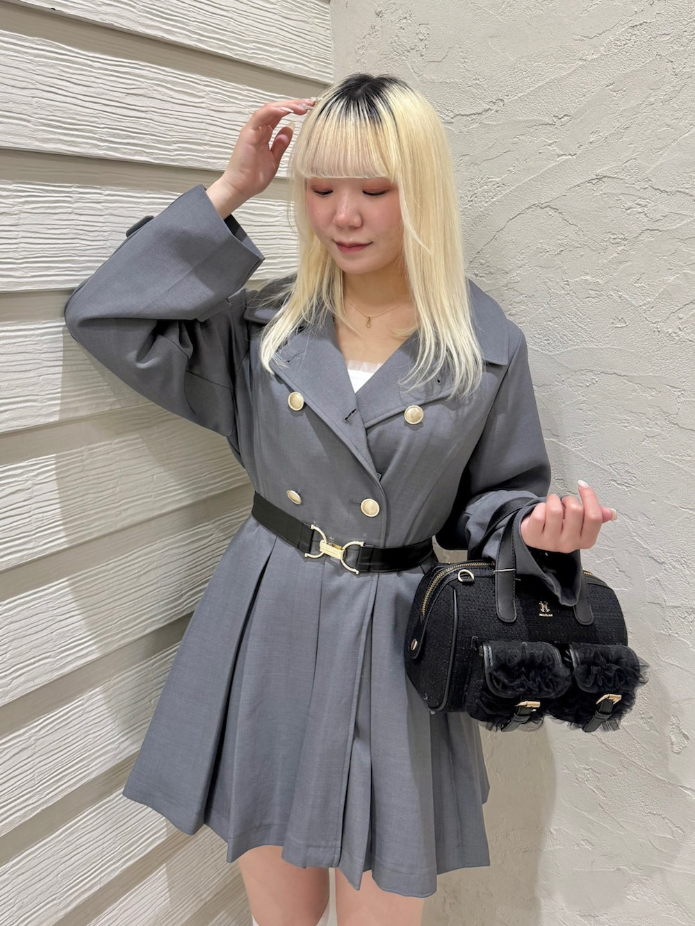 グレー系のトレンチコート、ホワイト系のTシャツ/カットソー、ブラック系のショルダーバッグを着用したレディースの春コーディネートの4枚目の写真