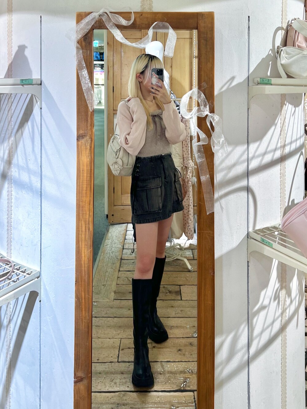 ピンク系のアンサンブル、ブラック系のスカート、ホワイト系のショルダーバッグを着用したレディースの秋コーディネートの2枚目の写真