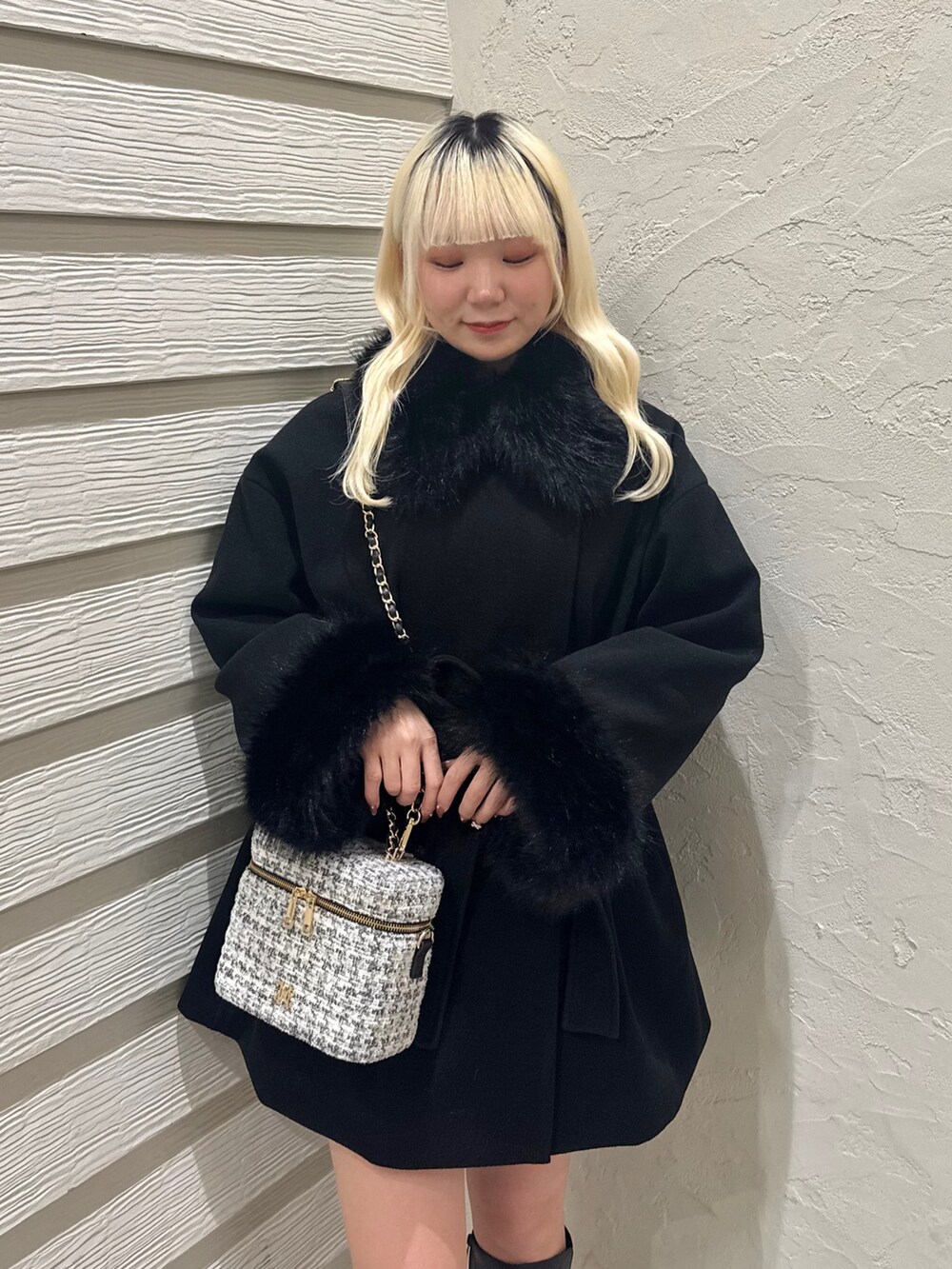 ホワイト系のニット/セーター、ブラック系のステンカラーコート、ホワイト系のショルダーバッグを着用したレディースの冬コーディネートの6枚目の写真