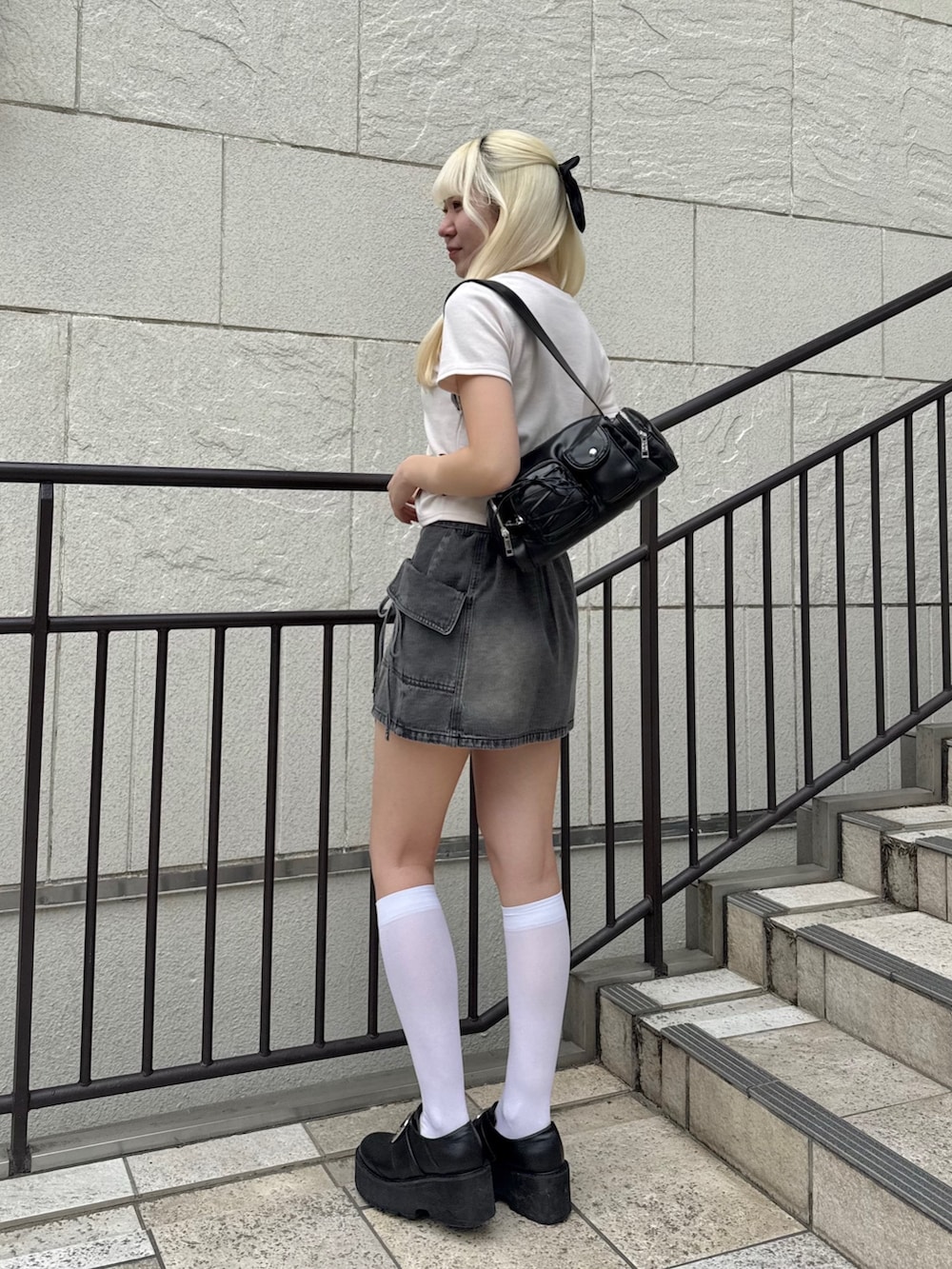 ブラック系のショルダーバッグ、ピンク系のTシャツ/カットソー、ブラック系のスカートを着用したレディースの春コーディネートの2枚目の写真