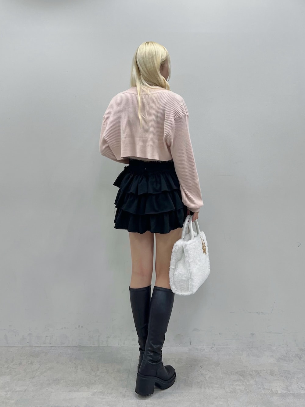 ホワイト系のトートバッグ、ピンク系のアンサンブル、ブラック系のスカートを着用したレディースの秋コーディネートの2枚目の写真