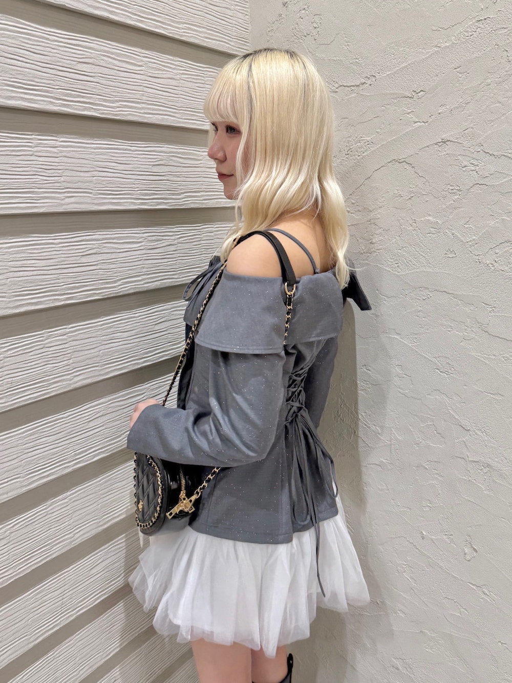 グレー系のワンピース、ブラック系のショルダーバッグ、ブラック系のブーツを着用したレディースの冬コーディネートの5枚目の写真