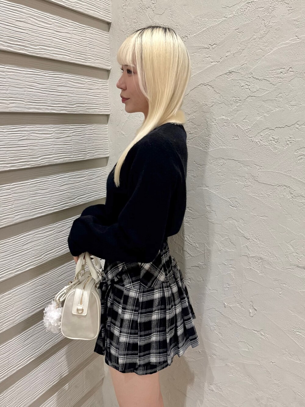 ブラック系のスカート、ホワイト系のボストンバッグ、ホワイト系のブーツを着用したレディースの秋コーディネートの5枚目の写真