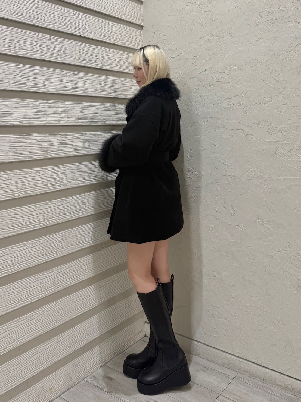 ホワイト系のニット/セーター、ブラック系のステンカラーコート、ホワイト系のショルダーバッグを着用したレディースの冬コーディネートの2枚目の写真