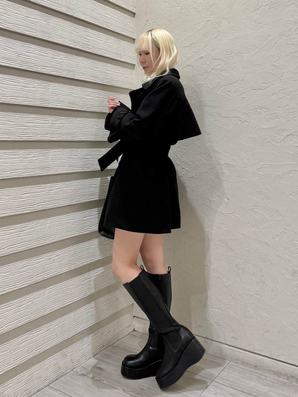 ブラック系のチェスターコート、ブラック系のトートバッグ、ホワイト系のアンサンブルを着用したレディースの冬コーディネートの2枚目の写真