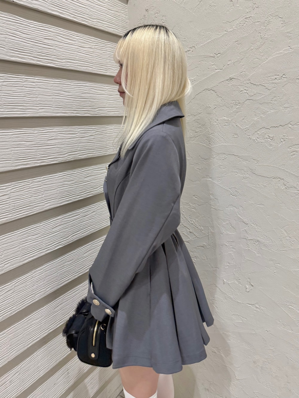 グレー系のトレンチコート、ホワイト系のTシャツ/カットソー、ブラック系のショルダーバッグを着用したレディースの春コーディネートの5枚目の写真