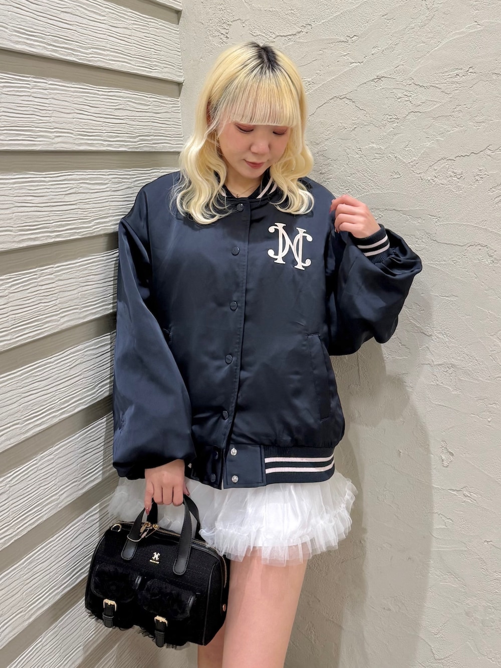 ブルー系のスカジャン、ホワイト系のスカート、ブラック系のスニーカーを着用したレディースの冬コーディネートの4枚目の写真