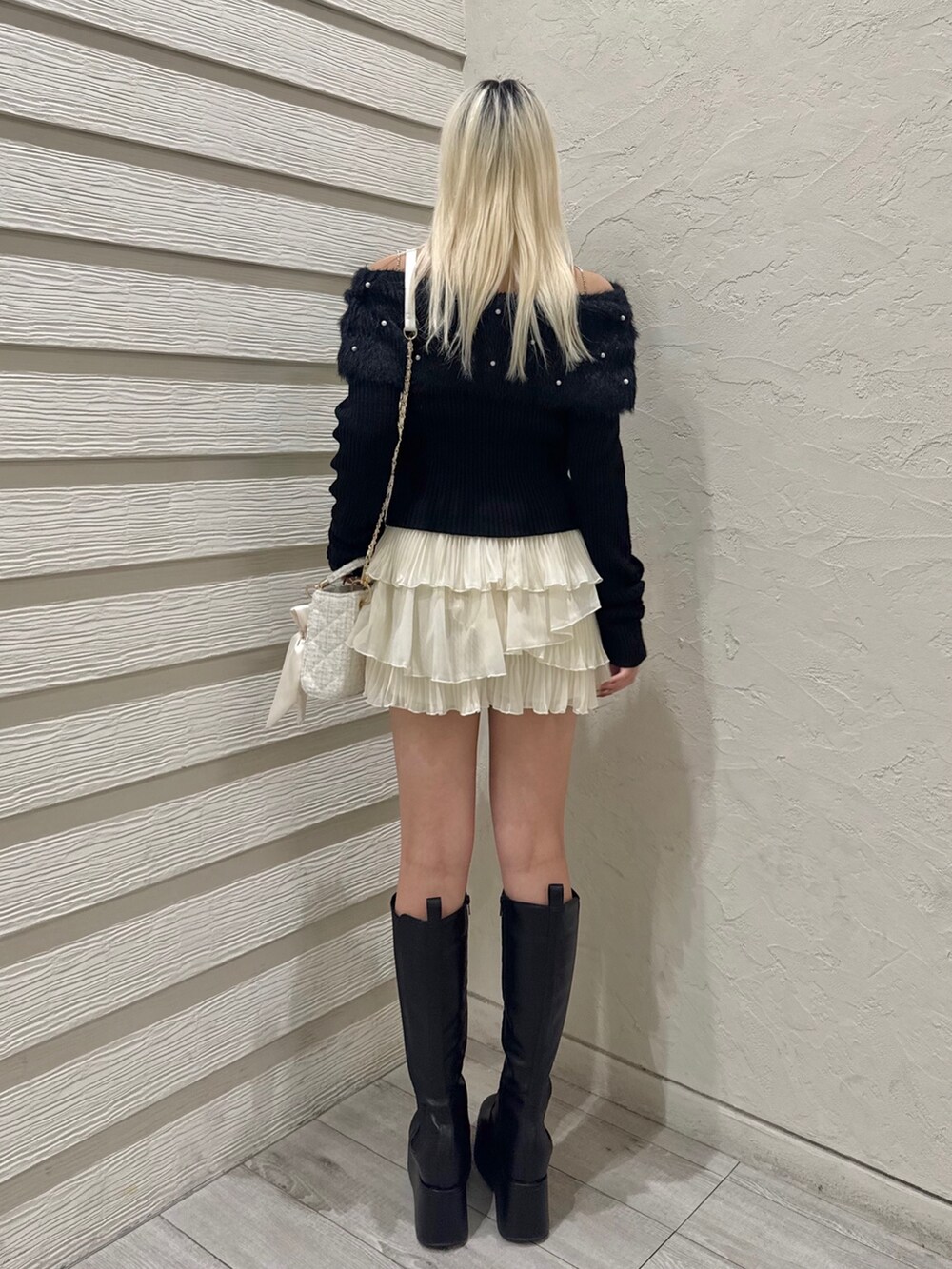 ブラック系のニット/セーター、ホワイト系のスカート、ホワイト系のショルダーバッグを着用したレディースの冬コーディネートの2枚目の写真
