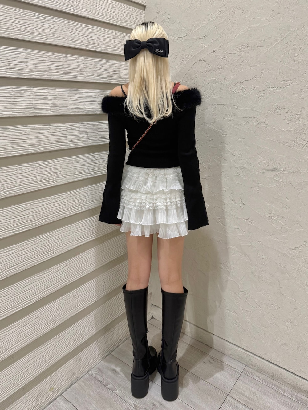 ブラック系のニット/セーター、ホワイト系のスカート、ブラック系のブーツを着用したレディースの秋コーディネートの3枚目の写真