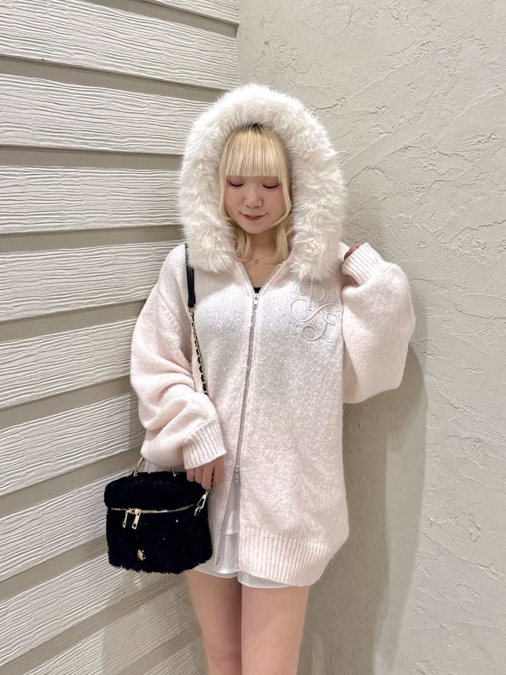 ピンク系のニット/セーター、ブラック系のショルダーバッグ、ホワイト系のブーツを着用したレディースの夏コーディネートの8枚目の写真