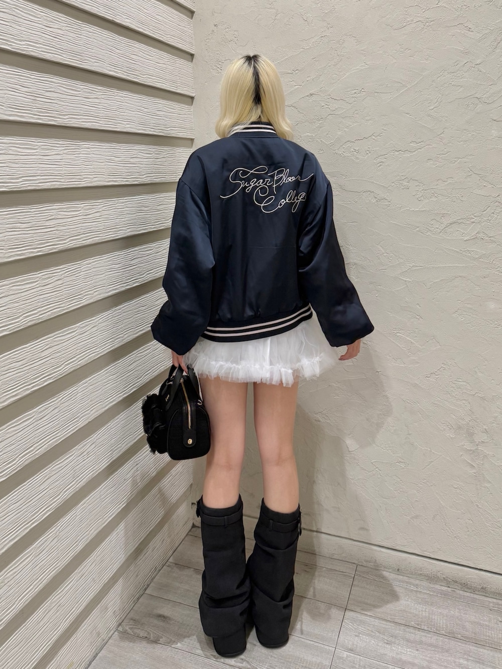 ブルー系のスカジャン、ホワイト系のスカート、ブラック系のスニーカーを着用したレディースの冬コーディネートの3枚目の写真