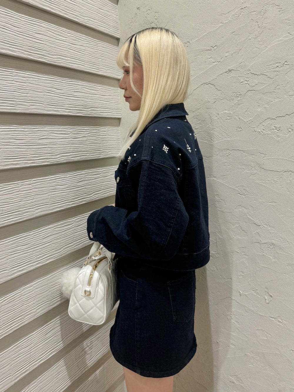 ブルー系のデニムジャケット、ブルー系のデニムスカート、ホワイト系のボストンバッグを着用したレディースの冬コーディネートの5枚目の写真