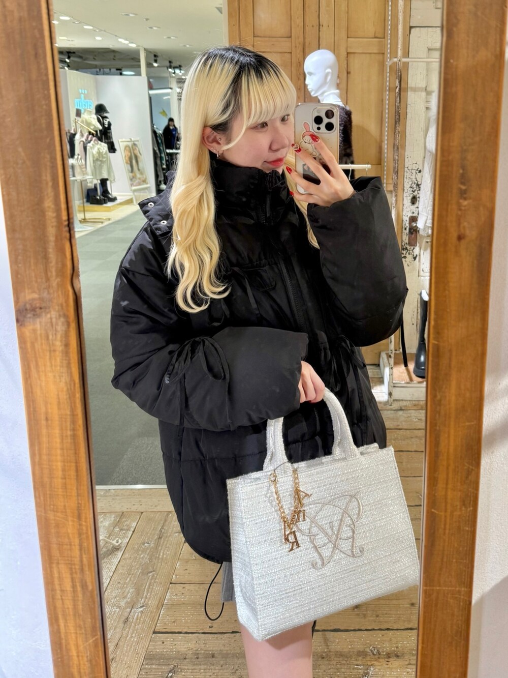 ブラック系のダウンジャケット/コート、グレー系のスカート、ホワイト系のトートバッグを着用したレディースの冬コーディネートの2枚目の写真