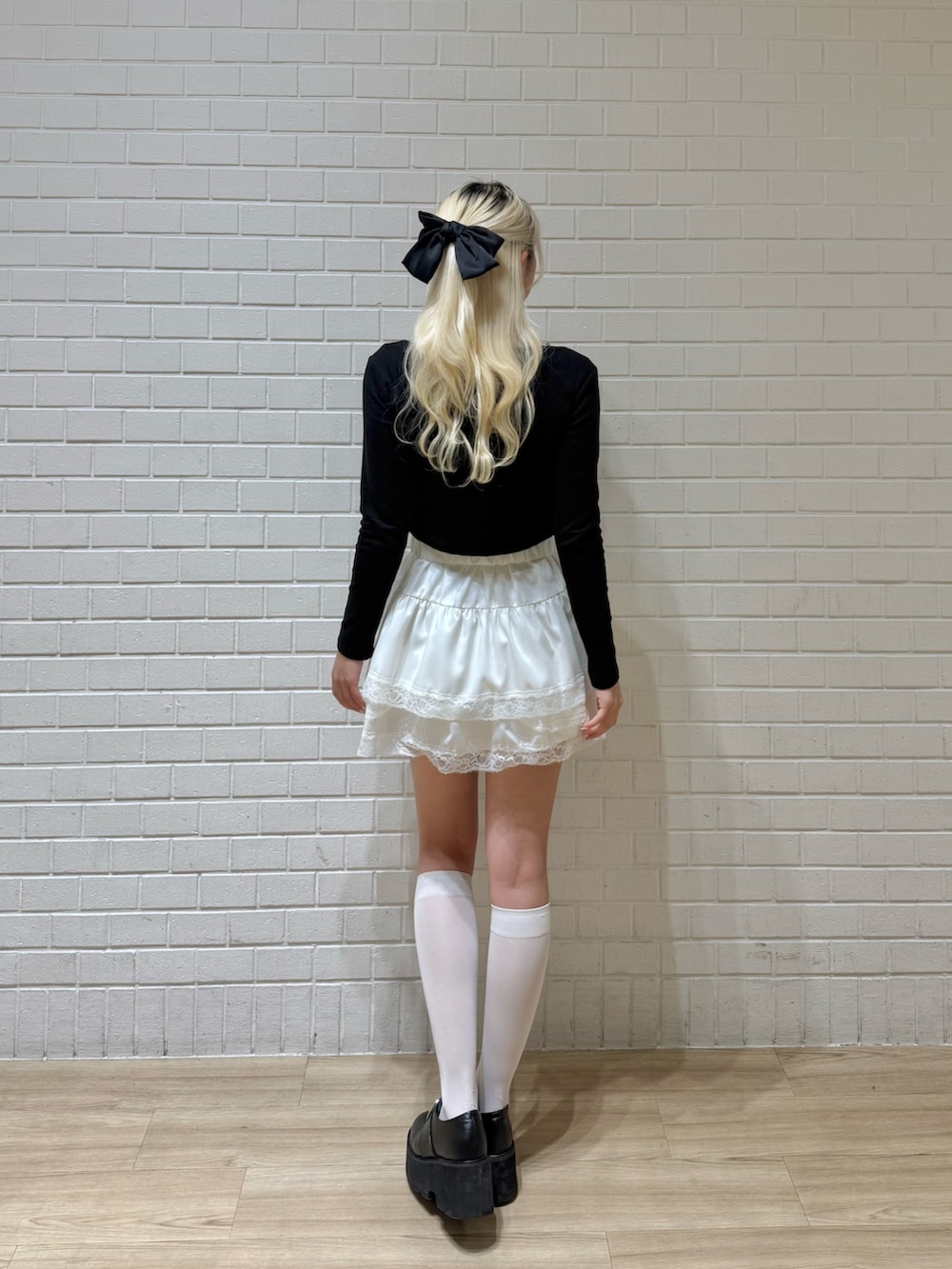 ホワイト系のスカート、ブラック系のTシャツ/カットソーを着用したレディースの冬コーディネートの2枚目の写真