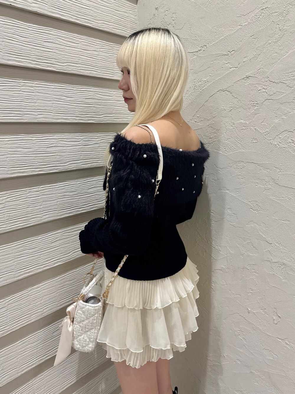 ブラック系のニット/セーター、ホワイト系のスカート、ホワイト系のショルダーバッグを着用したレディースの冬コーディネートの5枚目の写真