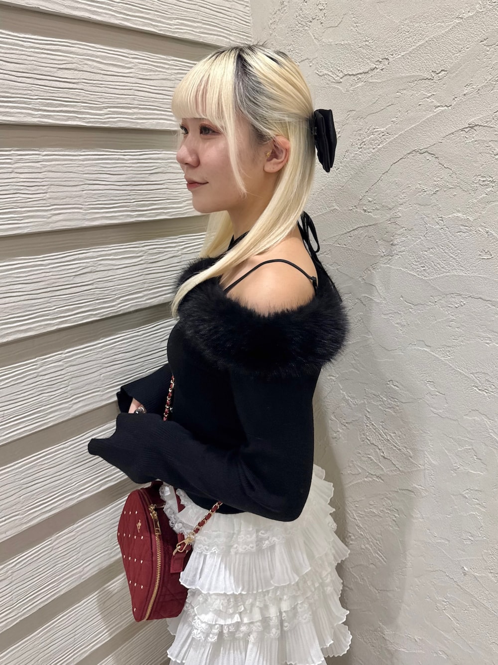 ブラック系のニット/セーター、ホワイト系のスカート、ブラック系のブーツを着用したレディースの秋コーディネートの5枚目の写真