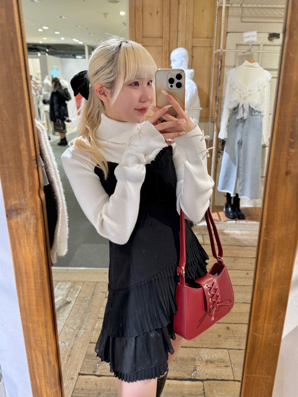 レッド系のショルダーバッグ、ブラック系のワンピース、ホワイト系のニット/セーターを着用したレディースの冬コーディネートの2枚目の写真