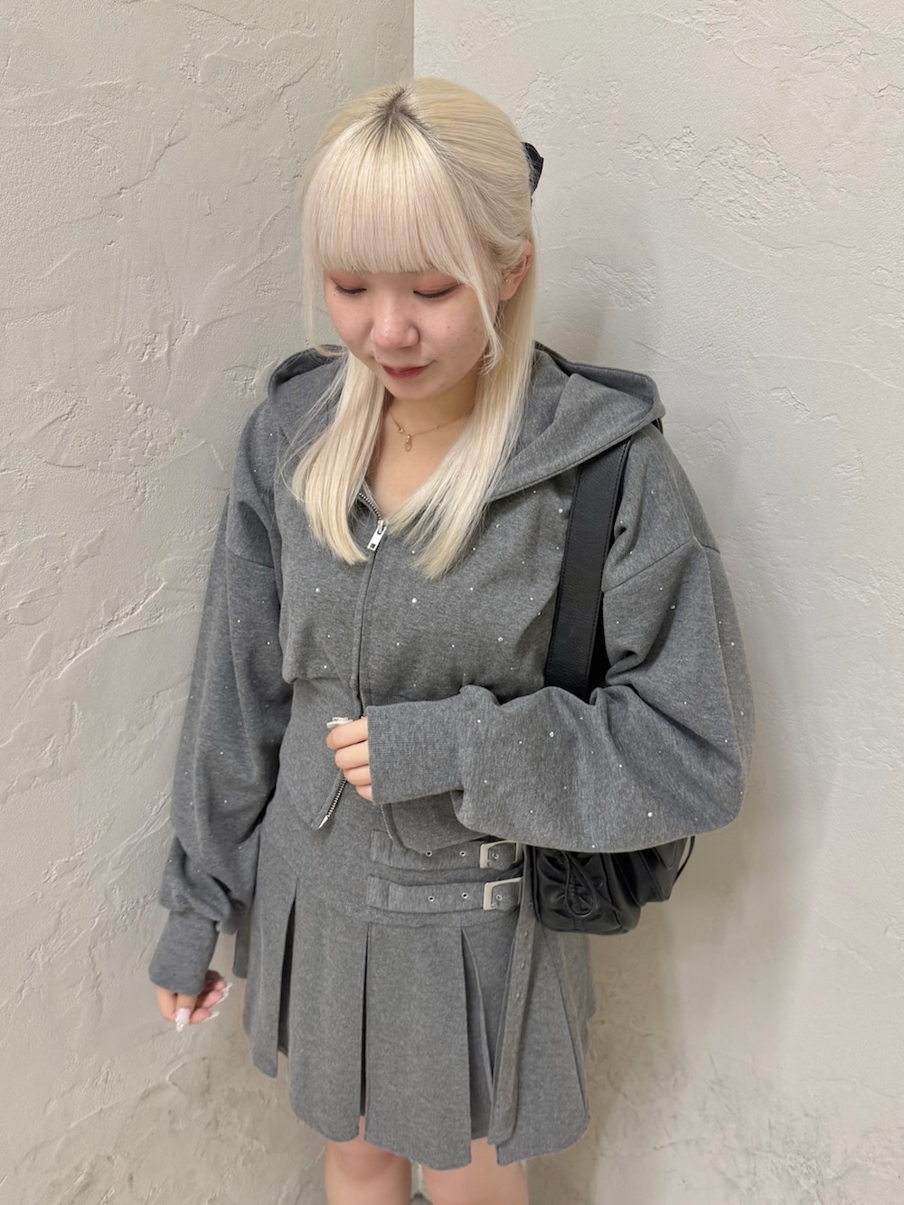 ブラック系のショルダーバッグ、グレー系のパーカー、グレー系のスカートを着用したレディースの秋コーディネートの5枚目の写真
