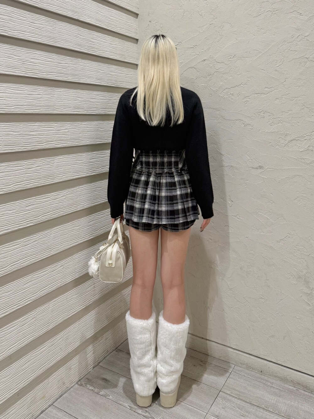 ブラック系のスカート、ホワイト系のボストンバッグ、ホワイト系のブーツを着用したレディースの秋コーディネートの3枚目の写真