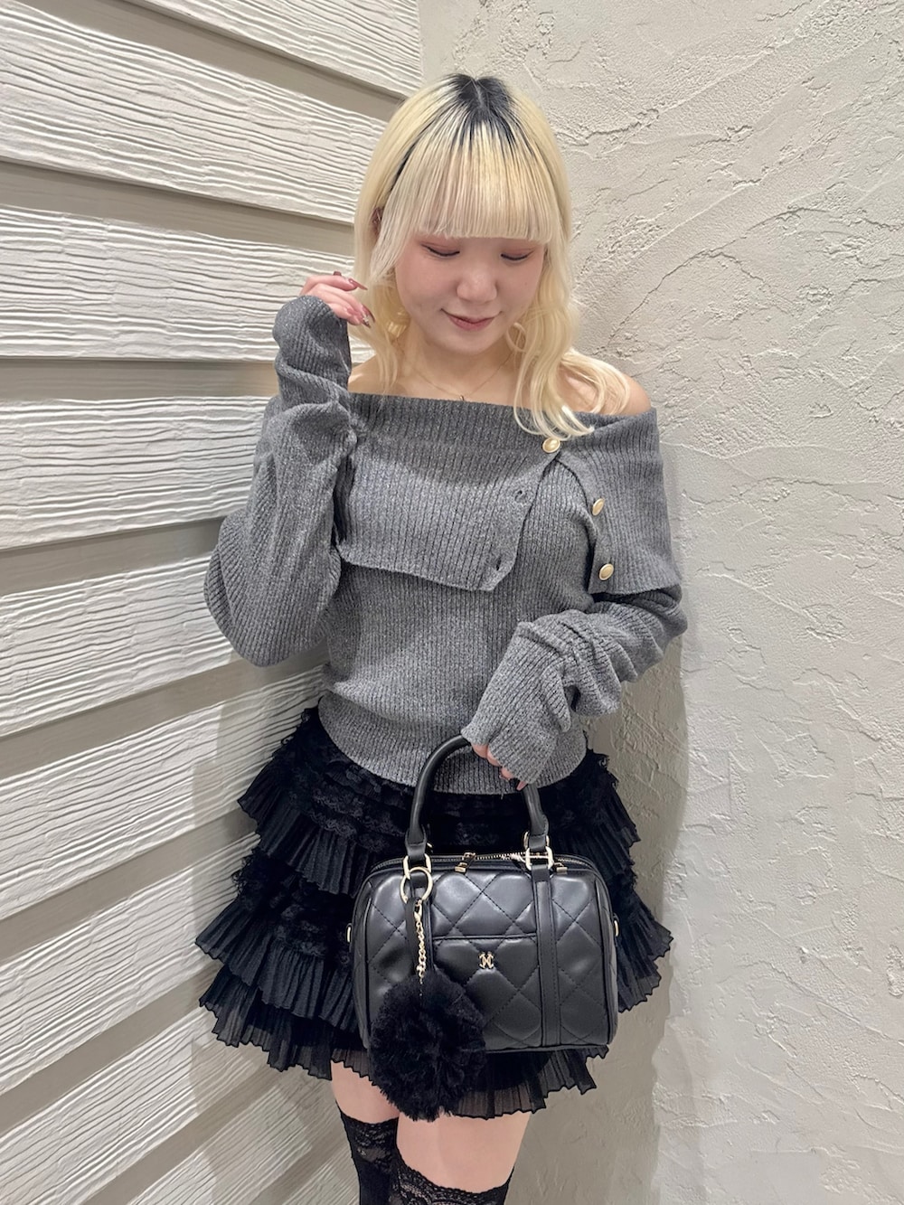 グレー系のニット/セーター、ブラック系のスカート、ブラック系のボストンバッグを着用したレディースの冬コーディネートの4枚目の写真