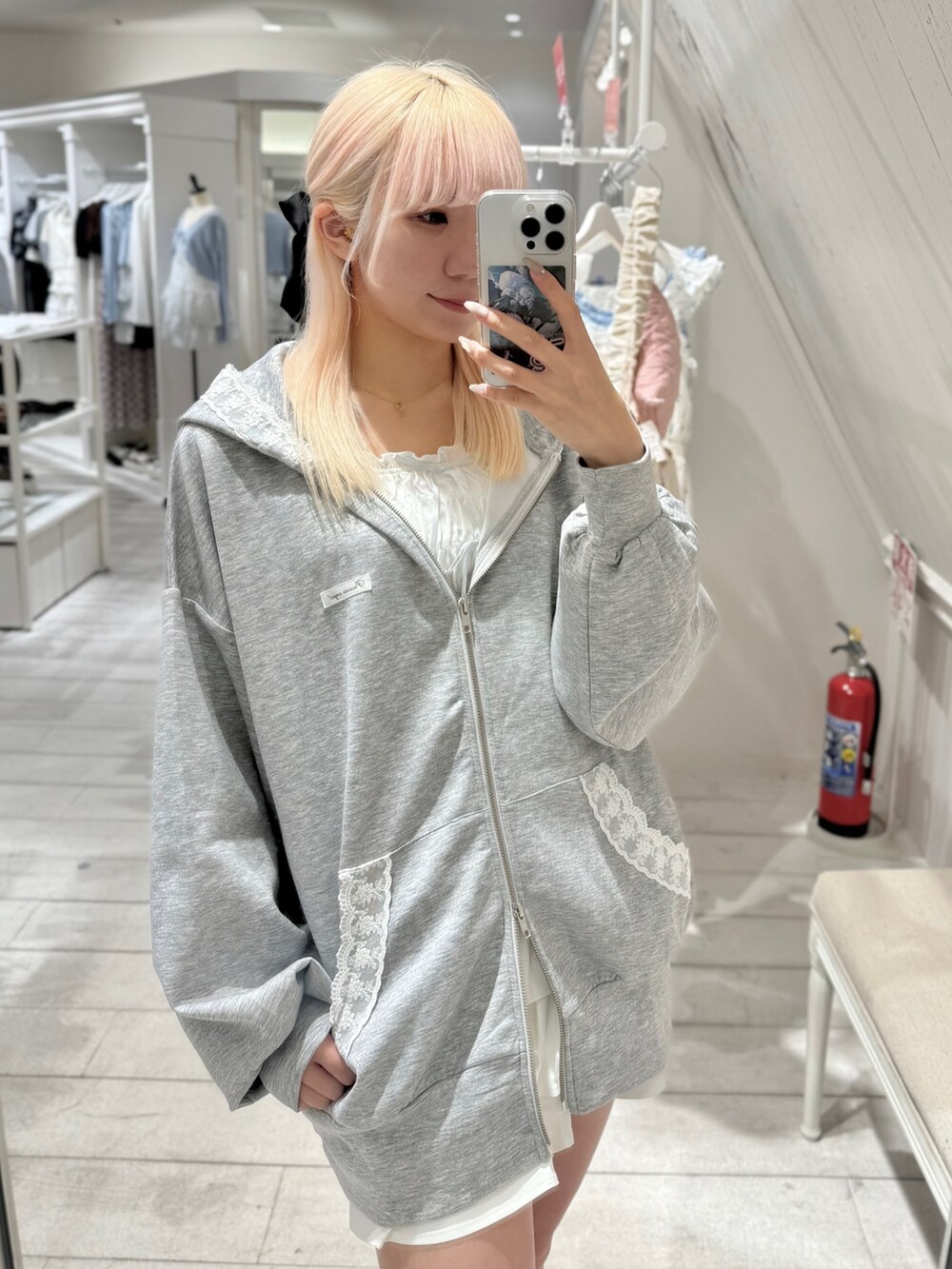 グレー系のパーカー、ホワイト系のキャミソール、ホワイト系のスカートを着用したレディースの夏コーディネートの3枚目の写真