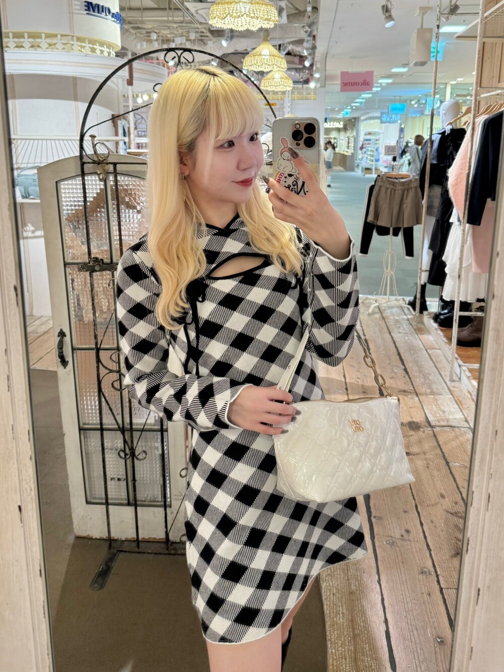 ブラック系のワンピース、ホワイト系のショルダーバッグ、ブラック系のブーツを着用したレディースの秋コーディネートの3枚目の写真