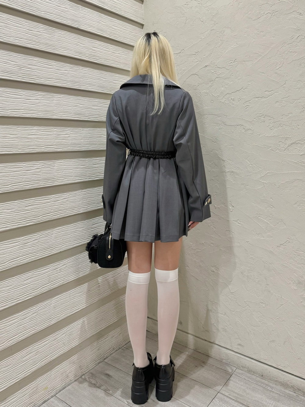 グレー系のトレンチコート、ホワイト系のTシャツ/カットソー、ブラック系のショルダーバッグを着用したレディースの春コーディネートの2枚目の写真