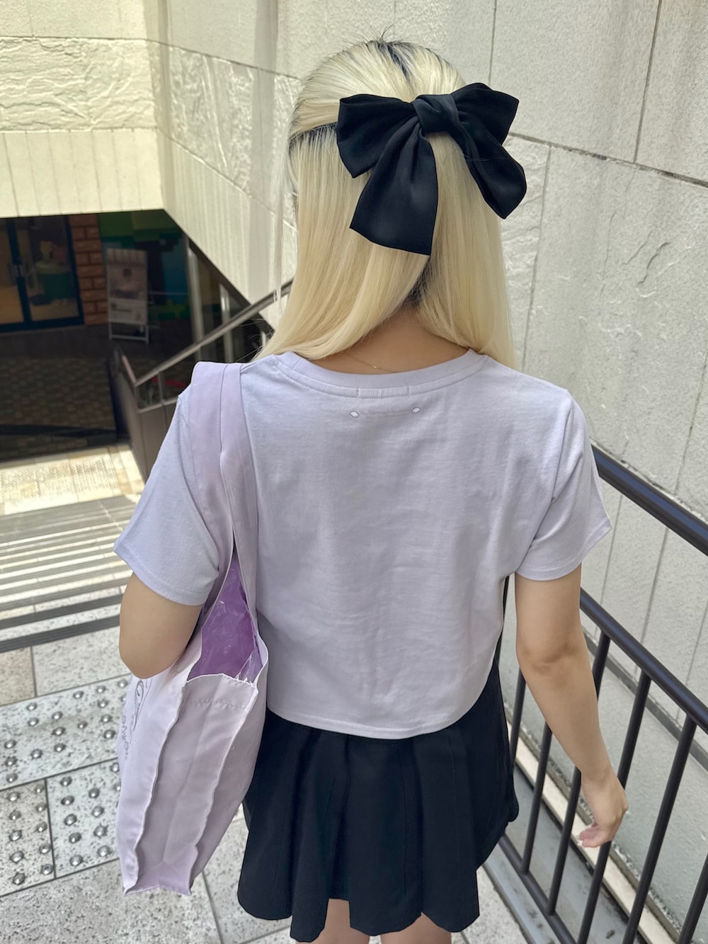 パープル系のトートバッグ、パープル系のTシャツ/カットソー、ブラック系のスカートを着用したレディースの夏コーディネートの7枚目の写真